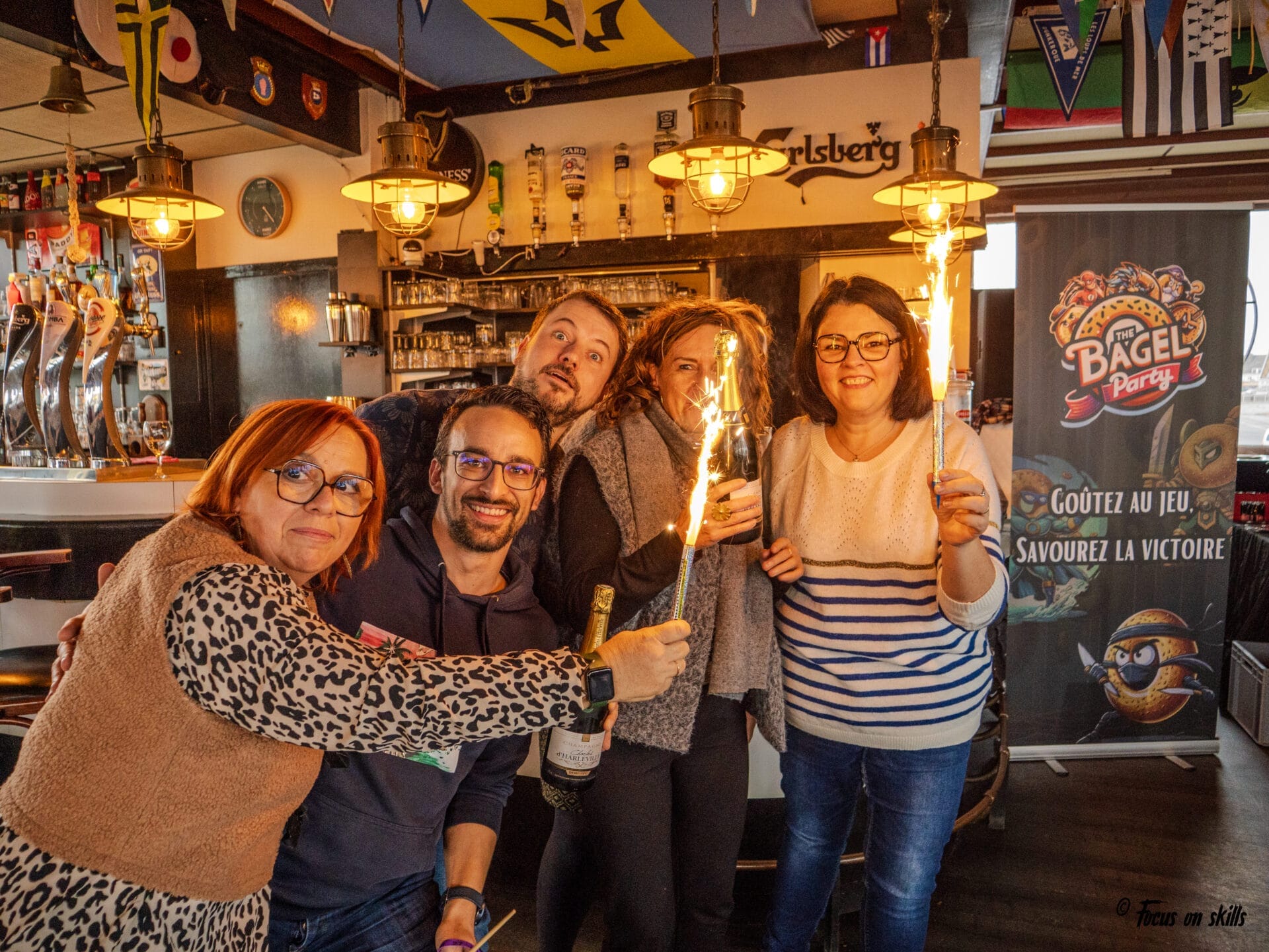 Participants qui célèbrent leur victoire avec des cierges magiques pendant une soirée Bagel Party animée par Focus on Skills